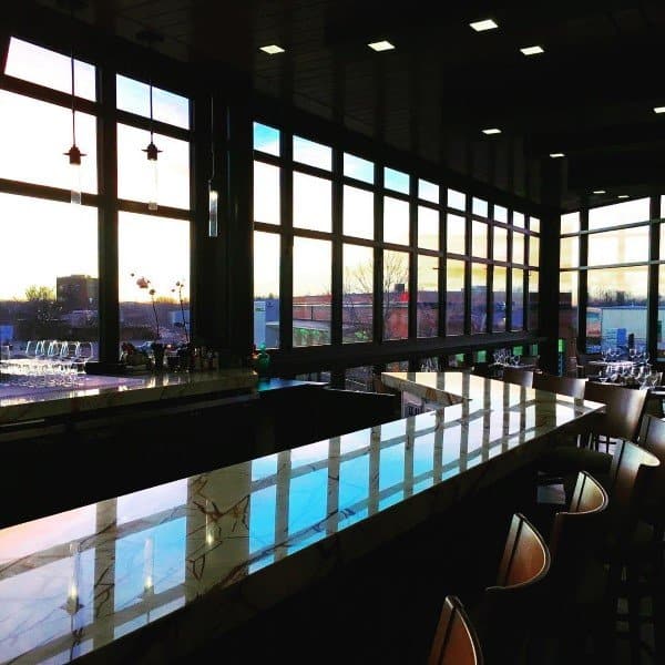 Long marble bar top in a modern space with large windows and contemporary lighting.