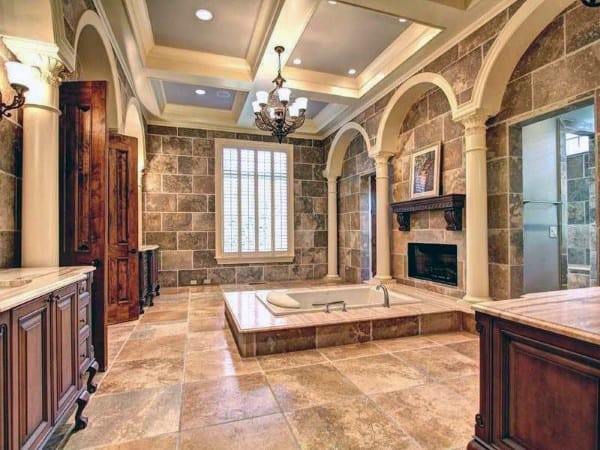 Luxurious bathroom with coffered ceiling, recessed coves, built-in tub, and stone walls.