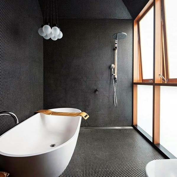 Modern black bathroom with freestanding tub, textured walls, and large frosted windows.