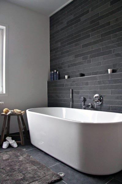Modern bathroom design featuring a sleek white freestanding tub against a dark gray tiled wall for a stylish, minimalist vibe.