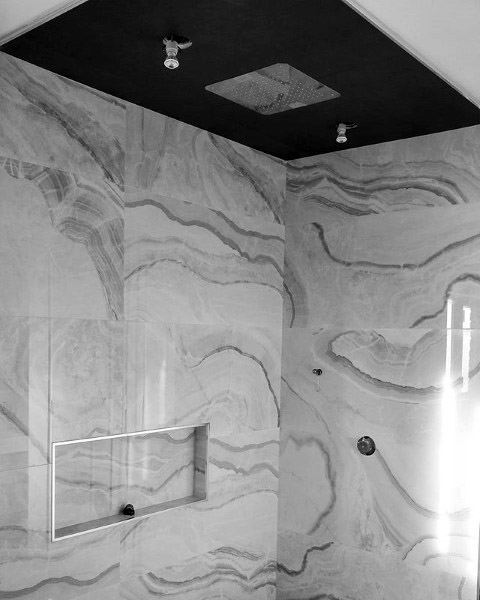 Black and white shower with marble-patterned walls and a sleek recessed shelf in the shower area