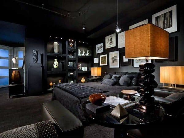 Dark masculine bedroom with black decor, modern art, and warm accent lighting.