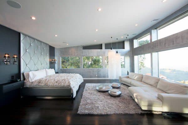 Spacious bedroom with tufted headboard, glass windows, and modern white couch.