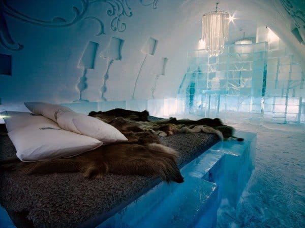 Ice-themed bedroom with fur bedding, ice furniture, and a crystal chandelier.