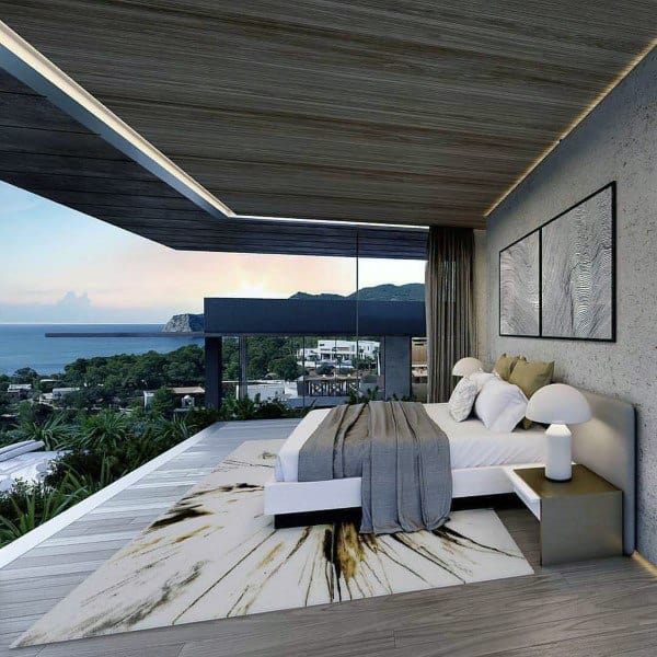 Modern bedroom with glass walls, ocean view, and stylish decor.