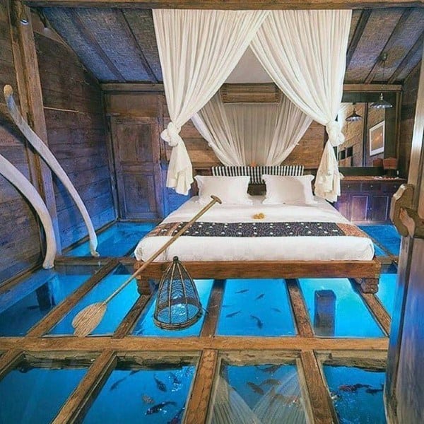 Rustic bedroom with canopy bed, glass floor, and underwater ocean view.