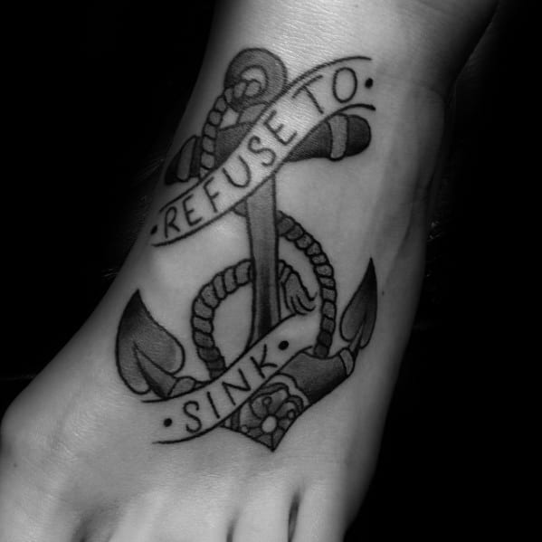 Black and white tattoo of an anchor with "Refuse to Sink" on a person's foot