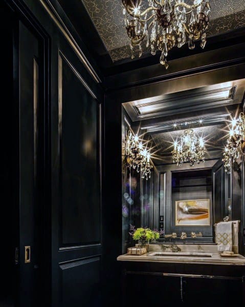Luxurious black bathroom with chandeliers, mirrored walls, and elegant gold accents.