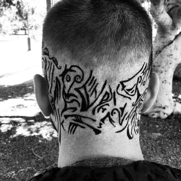 Back of a person's head with intricate black tribal-style tattoo designs on a shaved area
