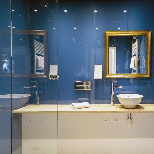 Bathroom with glossy blue walls, gold-framed mirror, vessel sink, and modern fixtures.