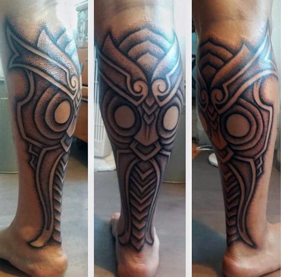 Intricate tribal-inspired calf tattoo with bold black outlines, geometric shapes, and shaded dotwork for a striking design