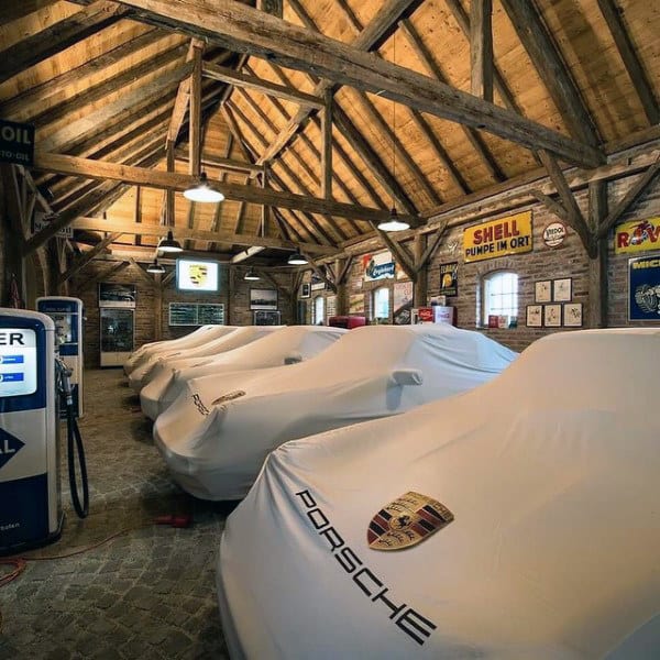 A rustic barn-style garage showcasing covered luxury cars under wooden beams with vintage decor.