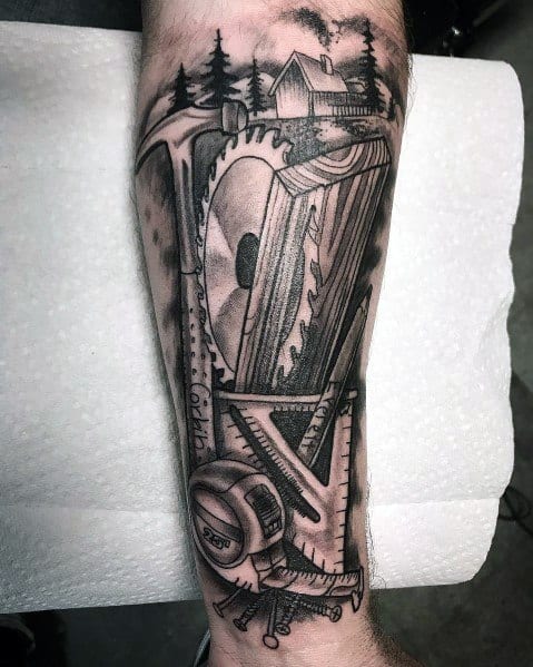 Detailed black and gray tattoo featuring a hammer, saw blade, ruler, and a cabin in the woods, symbolizing craftsmanship and traditional woodworking.