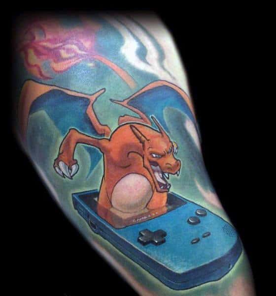 Charizard emerging from a blue Game Boy in a dynamic tattoo design, with wings spread and intense, fiery expression.