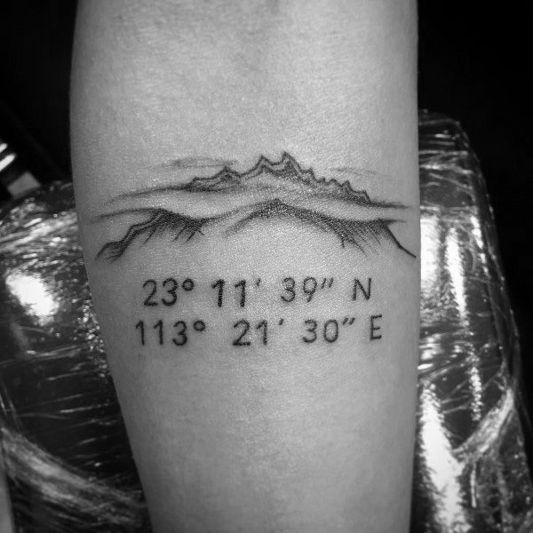 Coordinate tattoo on a forearm featuring a detailed mountain range sketch, symbolizing a special location with geographic coordinates.