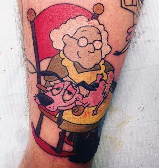 Courage the Cowardly Dog tattoo featuring Courage resting on Muriel’s lap as she sits smiling in a red rocking chair.
