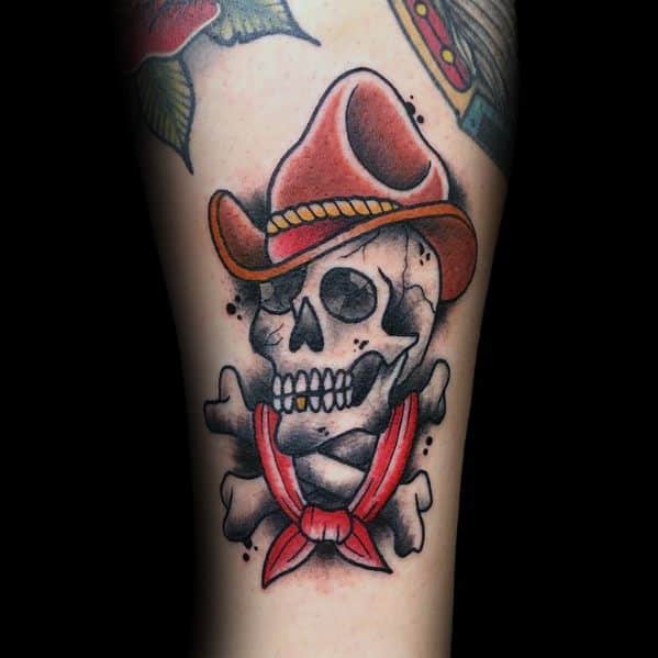 Tattoo of a cowboy-themed skull wearing a hat, with crossed bones and a red bandana. A bold Western-style design with shading details.