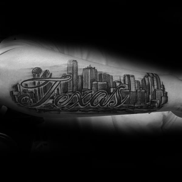 Detailed Dallas skyline forearm tattoo with bold "Texas" script overlay, featuring iconic skyscrapers in black and gray shading.
