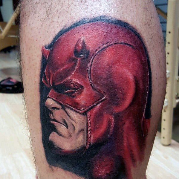 Realistic Daredevil tattoo with deep red tones, bold shadows, and a fierce expression showing determination and strength.