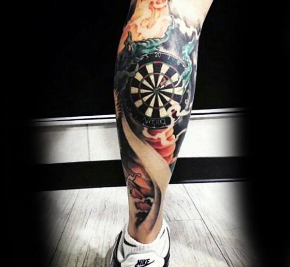 Colorful leg tattoo featuring a detailed dartboard surrounded by vibrant flames, smoke, and dramatic shading for a bold statement.