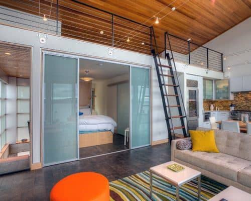 Modern loft with sliding glass bedroom doors, ladder access, and colorful furniture accents.