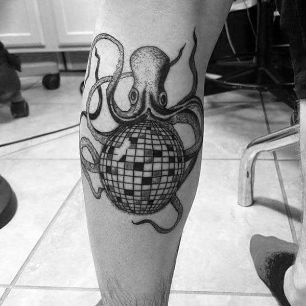 Black and grey tattoo of an octopus holding a disco ball on a man's leg, blending marine and retro themes with intricate shading.