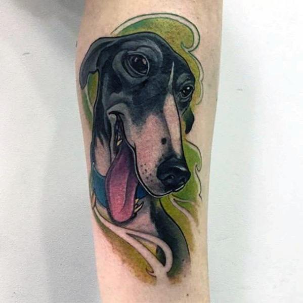 A colorful greyhound tattoo with a playful expression, showcasing the dog's face with vibrant green and blue accents around it.