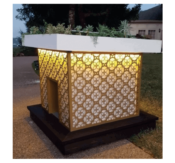 Illuminated dog house with a decorative lattice design and lush plants gracing the roof