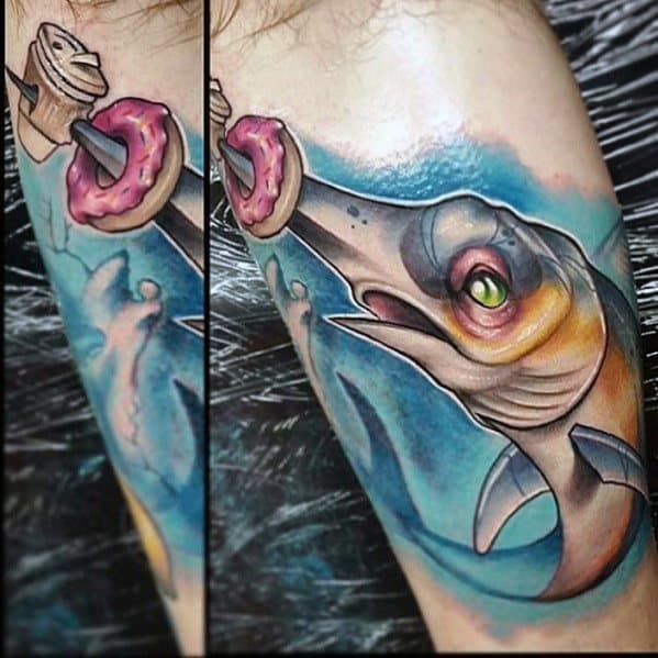Vibrant tattoo of a swordfish leaping toward a pink frosted donut on a hook, set against a bold blue ocean background.