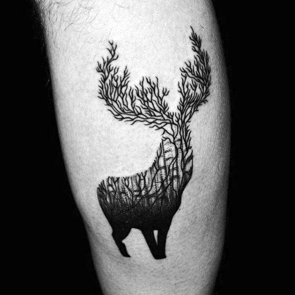 Black ink elk tattoo with antlers transforming into tree branches, creating a surreal and nature-inspired design on a man's leg.