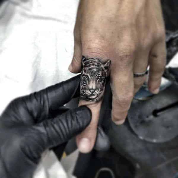 Hand with a detailed tiger tattoo on the index finger