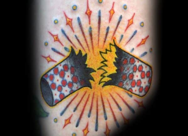 Tattoo of a firecracker bursting apart with vibrant sparks and explosion lines, done in a bold traditional style with red and yellow details.