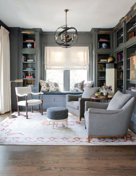 Cozy living room with gray chairs, window seat, bookshelf, and a decorative rug