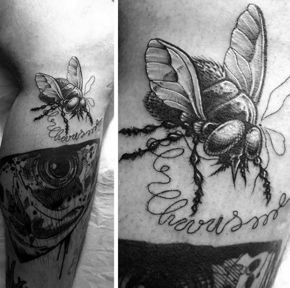 Realistic black and grey fly tattoo with detailed wings and legs, placed above cursive script on the thigh.
