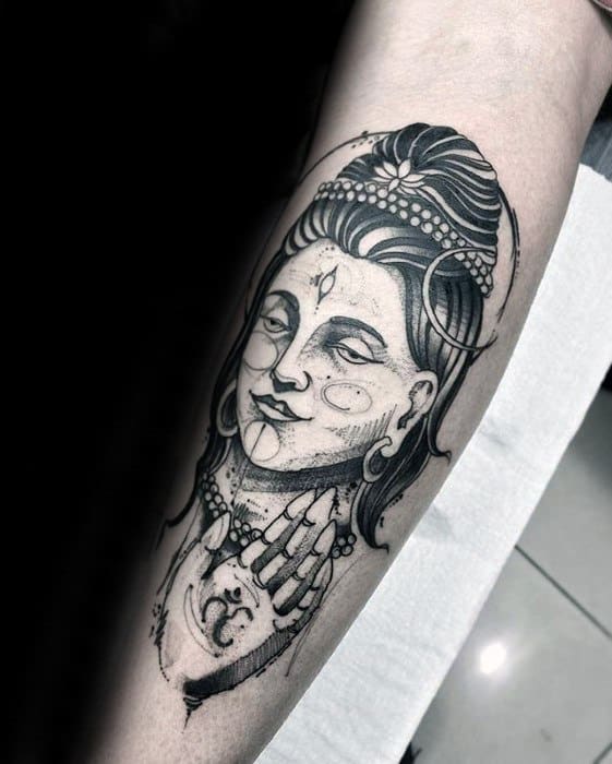 Lord Shiva tattoo featuring detailed linework with a serene expression, adorned with beads, crescent moon, and symbolic hand gesture.