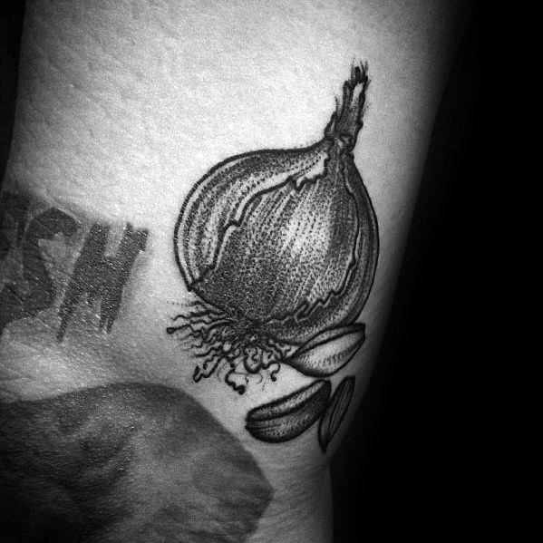 Detailed black and grey onion tattoo with fine linework and shading, featuring roots and cloves for a bold and artistic design.