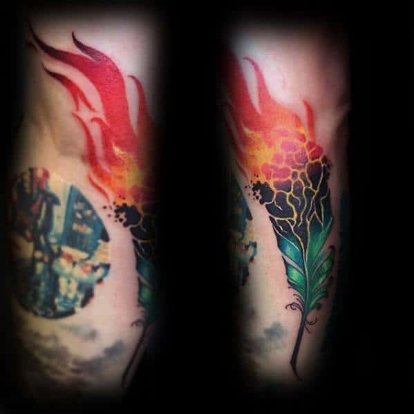 Gradient tattoo of a green feather transforming into fiery red and orange flames with honeycomb-like textures at the center.