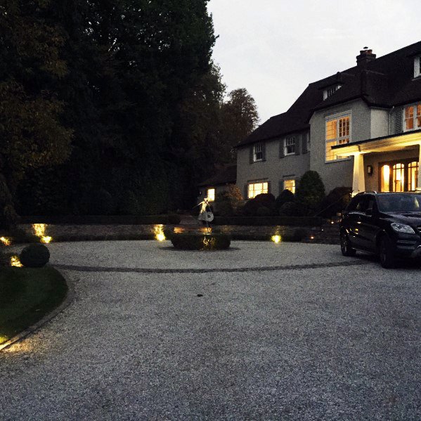 Elegant gravel driveway illuminated by landscape lighting, highlighting the driveway curves and garden features