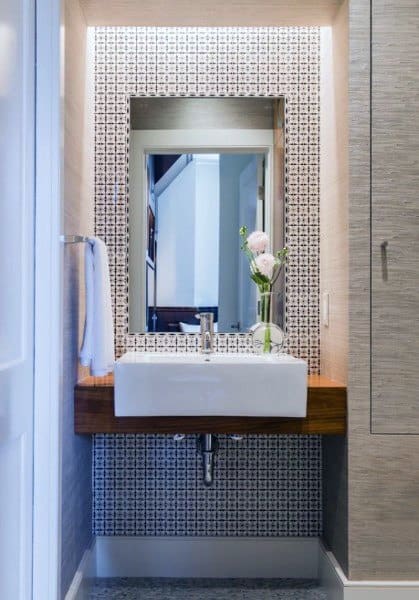 small bathroom sink with pattern tile accent wall