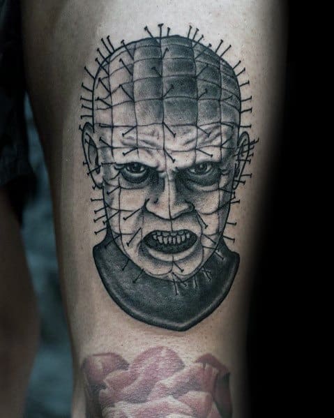 Black and grey tattoo of Pinhead from Hellraiser, featuring detailed shading and precise needle-like pins on his head for a striking look.