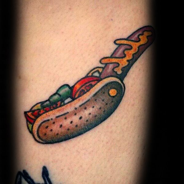 Hot dog tattoo featuring a sausage with ketchup and mustard, nestled in a poppy seed bun, with toppings like tomatoes and green onions.