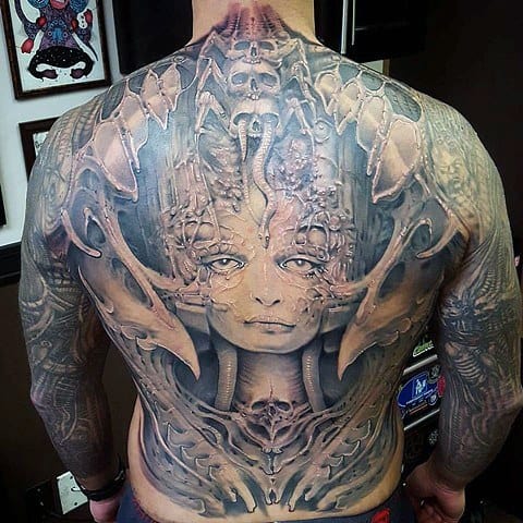 Full-back HR Giger-style tattoo featuring a haunting biomechanical female face fused with organic alien and mechanical elements.