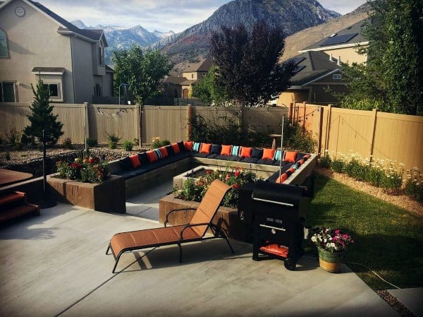 Backyard with sunken seating, colorful cushions, fire pit, grill, and mountain views.