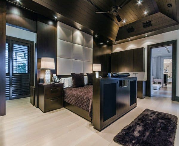 Elegant bedroom with dark wood accents, modern lighting, and plush textured decor.