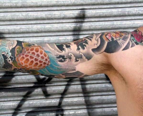 Japanese turtle tattoo sleeve with bold waves, blue accents, and intricate shell details, creating a striking and dynamic design.