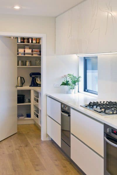 Compact kitchen pantry with open shelving and modern white cabinetry.