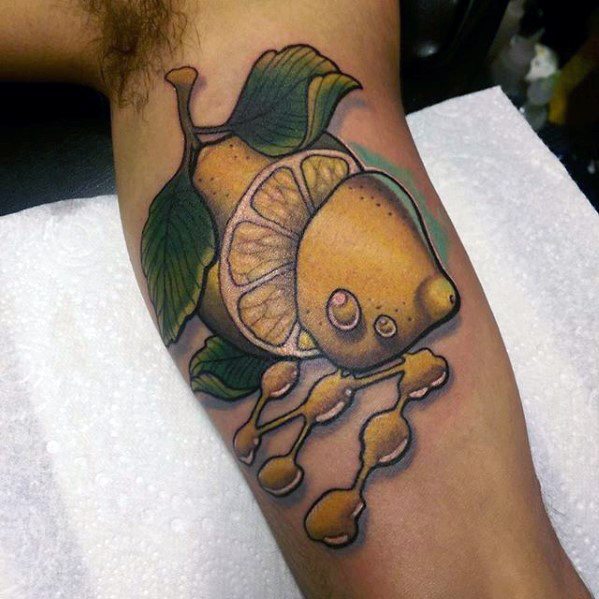Bold tattoo of a lemon transforming into a fish, with lemon slices, green leaves, and dripping honeycomb-style fins.