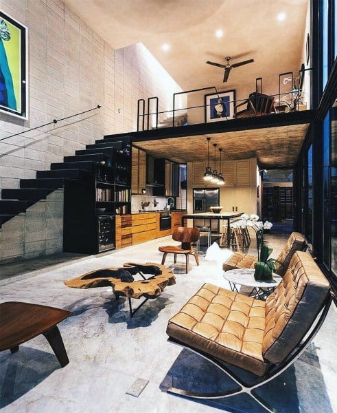 Industrial loft with open living space, modern furniture, and floating black staircase.
