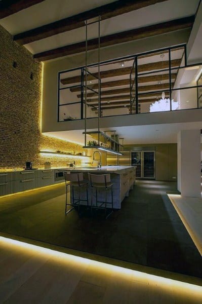 Modern loft kitchen with exposed beams, brick wall, and ambient LED lighting accents.