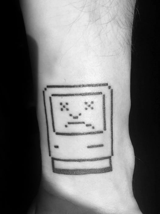 Minimalist black line tattoo of a classic Mac with a pixelated sad face, inspired by the vintage “Sad Mac” error screen.